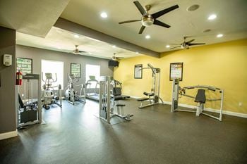 A gym with a variety of equipment including weights and cardio machines.